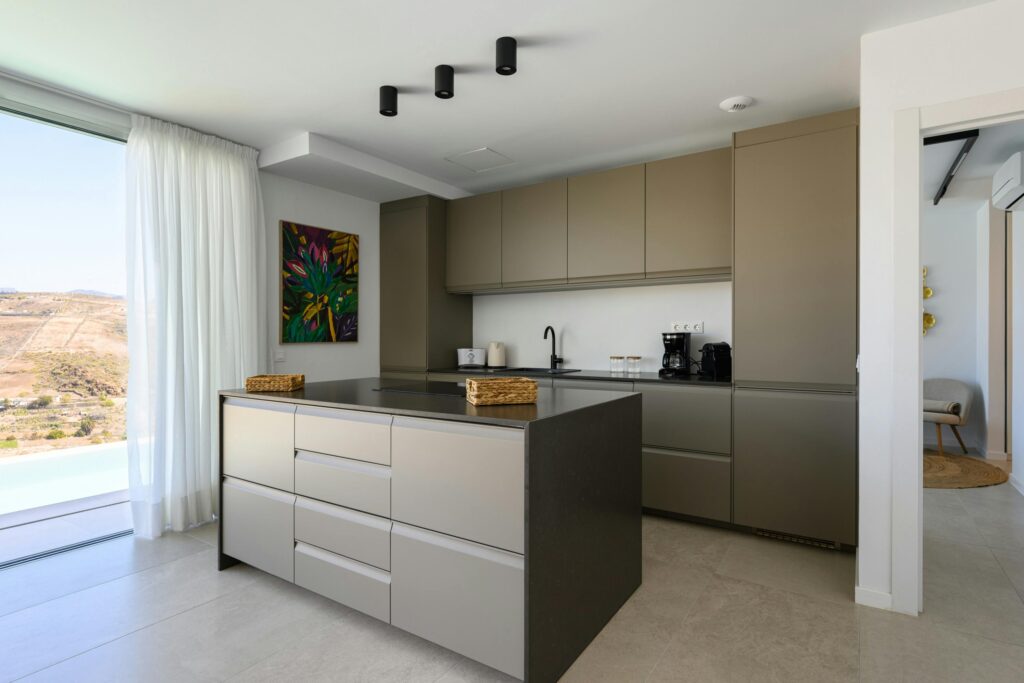A sleek, minimalist kitchen interior with modern cabinetry and a stunning outdoor view.
